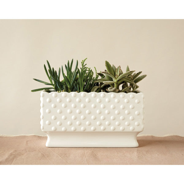 A white ceramic planter with a hobnail texture, scalloped edge, and polka dots.